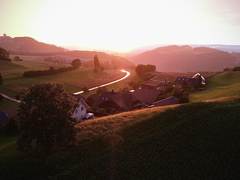 Der Weiler Englisberg im Abendlicht, dahinter die H&uuml;gel