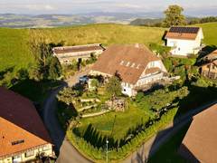 Luftaufnahme des Hofs Lindenrain mit den Alpen im Hintergrund